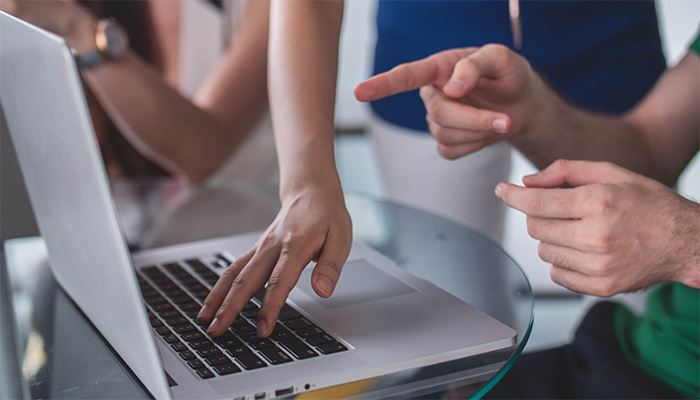 Händer som pekar och instruerar vid en datorskärm